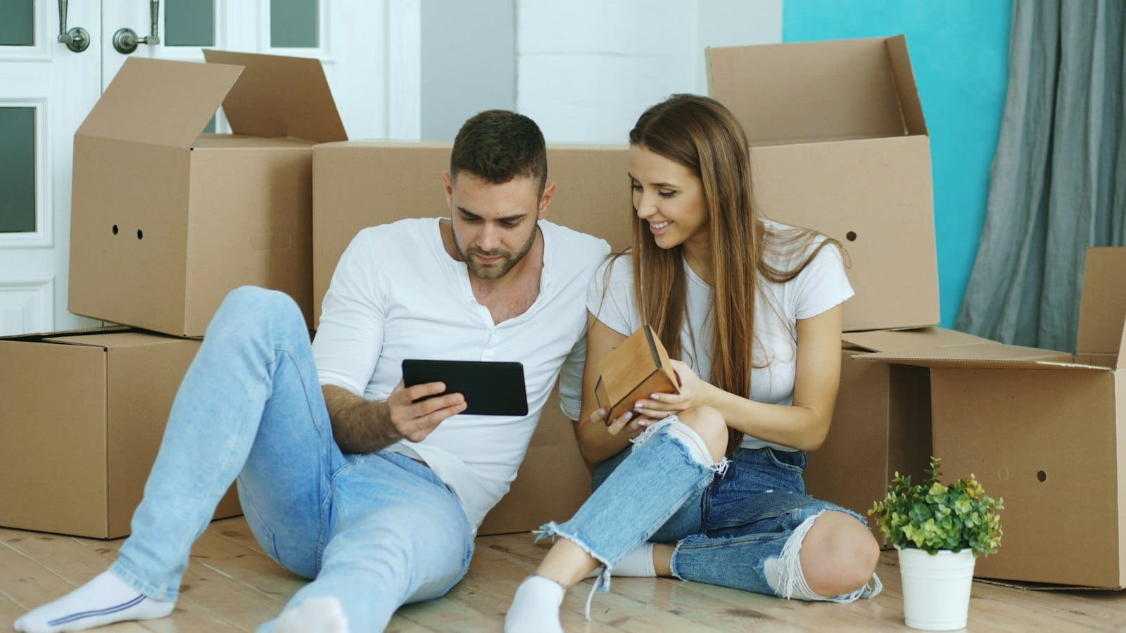 Young couple sitting among moving boxes after buying an apartment in the Sutherland Shire