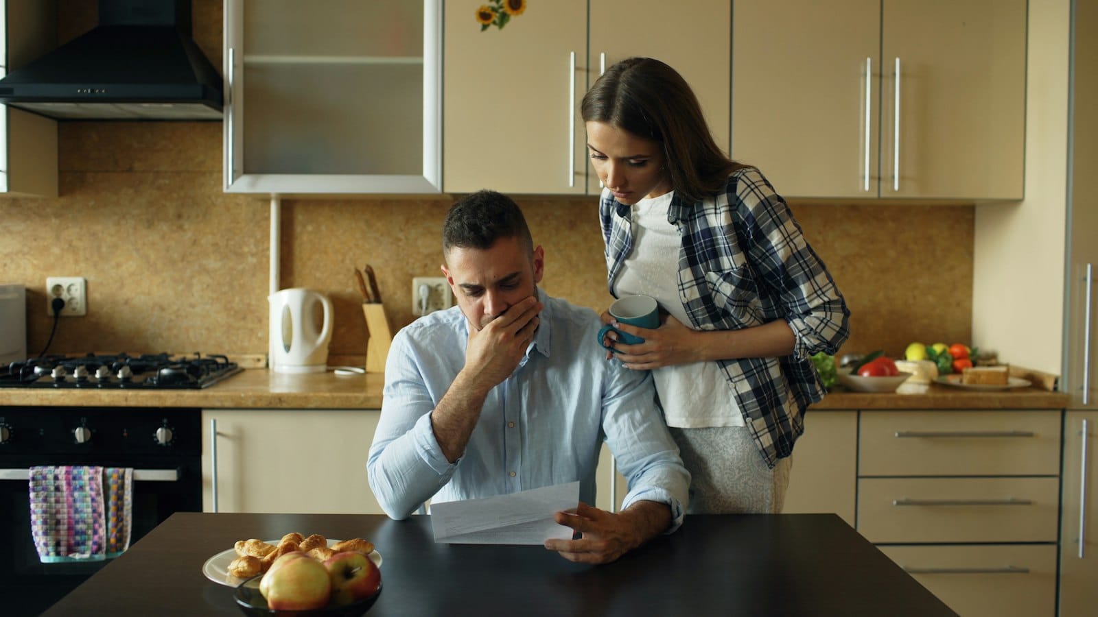 Couple reading a letter from their lender at the kitchen table as their fixed rate ending approaches