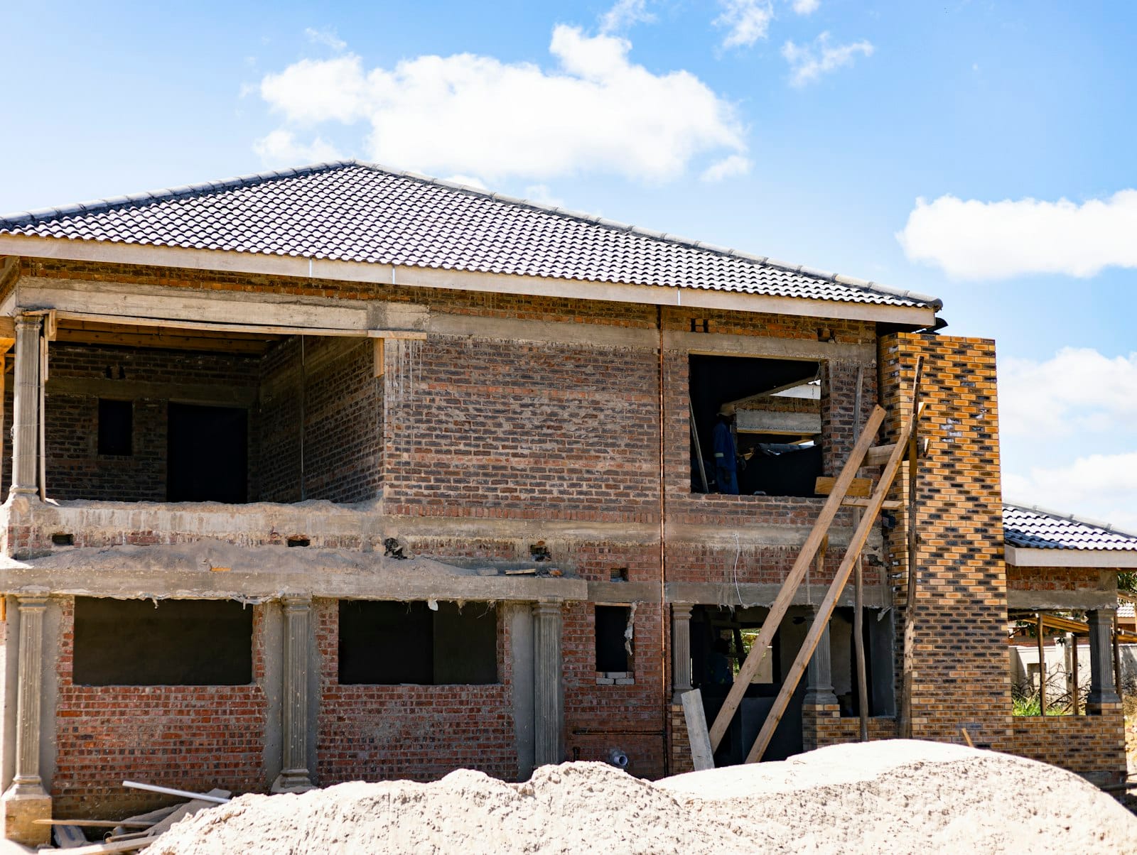 Two-storey brick house under construction with the roof on, a build stage where a construction loan progress payment is often drawn