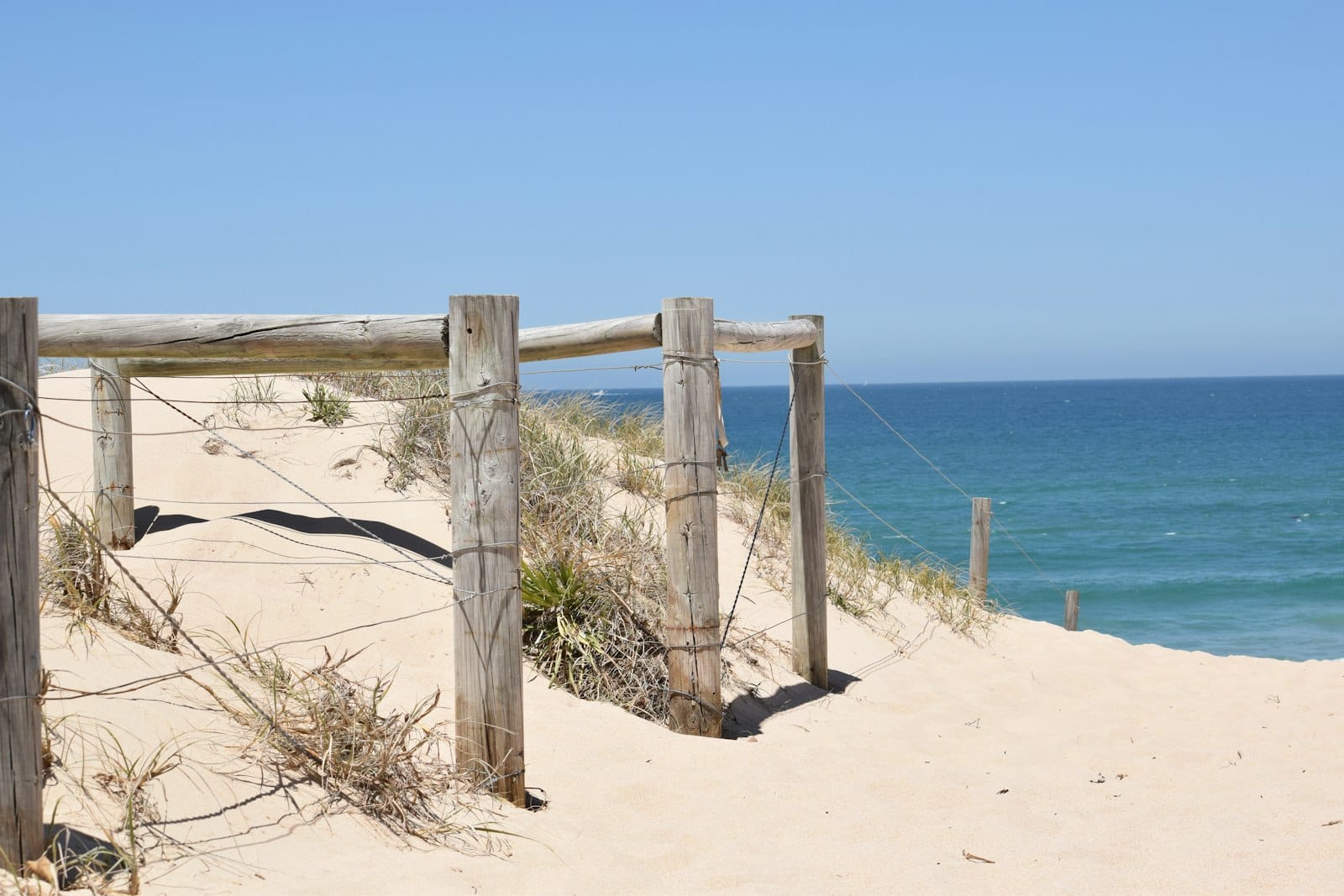 Wooden beach access gate on the sand dunes by the ocean, a coastal scene familiar to anyone using a mortgage broker in the Sutherland Shire