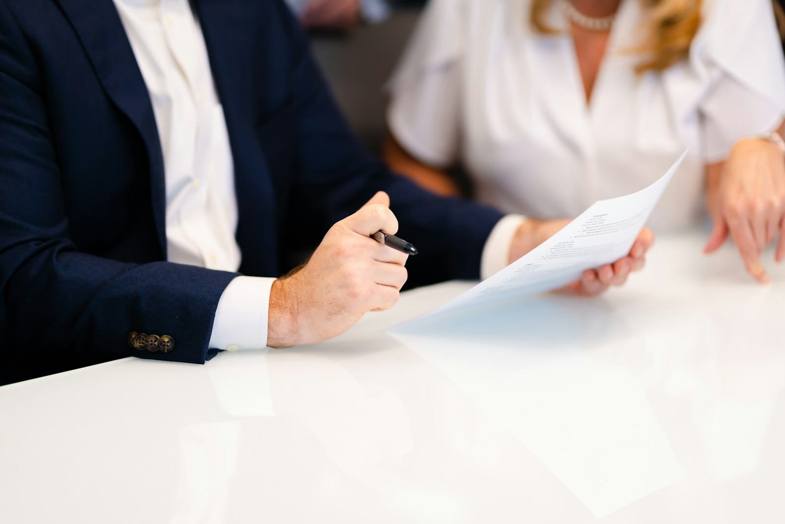 Couple reviewing and signing home loan paperwork at a white table, a good moment to check how long pre-approval lasts